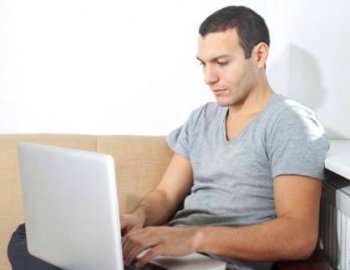 A multimedia designer works on his laptop on the couch